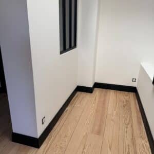 Parquet massif en pin maritime sans noeud largeur 200mm avec plinthes moulurées peintes en noir