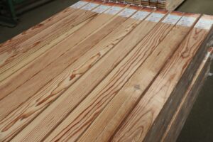 Piles de planches de bois naturel clair empilées, emballées avec leurs étiquettes produit visibles et grains apparents.
